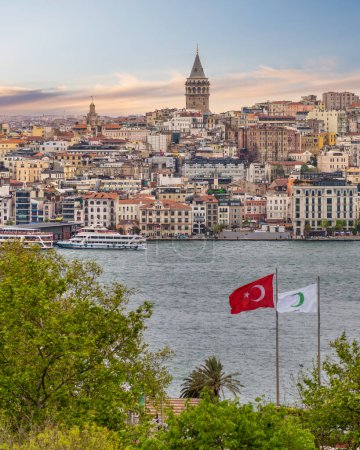 Skyline der europäischen Seite Istanbuls mit Fähren in der Bosporus-Meerenge, Galata-Turm ganz hinten und bewölktem Himmel an einem Frühlingstag nach Sonnenaufgang, Türkei