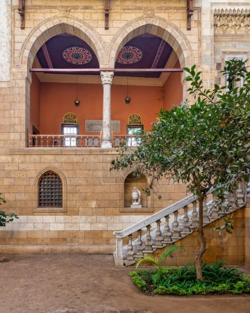 Patio sereno muestra la belleza atemporal de la arquitectura mameluca con grandes arcos altos y piedra con escalera acogedora que conduce a balcón adornado