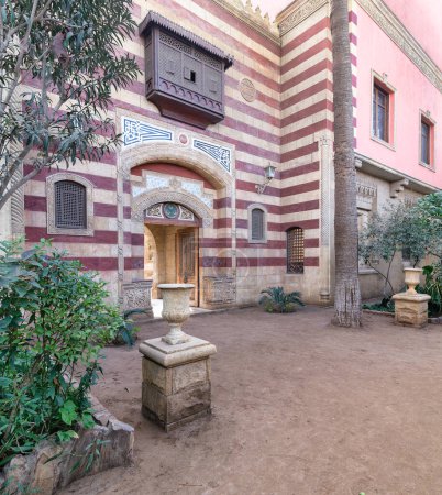 La llamativa entrada arqueada a rayas rojas y blancas conduce a un edificio de estilo mameluco, que muestra intrincados detalles arquitectónicos