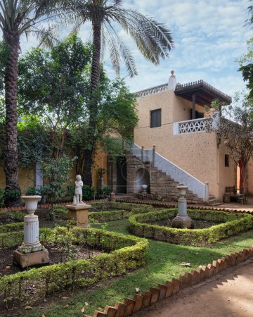 La exuberante vegetación enmarca el tranquilo jardín del Palacio del Príncipe Naguib en El Cairo, Egipto, mostrando elementos arquitectónicos mamelucos clásicos