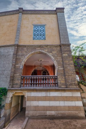 A serene view of a rustic style building featuring an arched wooden balcony, and detailed window grills
