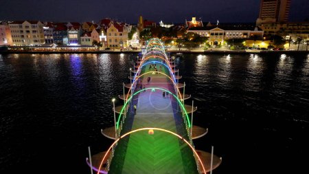 Pasarela iluminada en Otrobanda en Willemstad Curazao. Cityscape Skyline. Noche en el centro. Otrobanda en Willemstad Curacao. Puente flotante Landmark. Edificios luminosos.