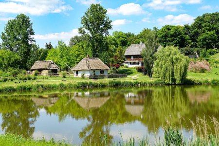 Photo for Traditional wooden houses reflected i a pond. The Open Air Folk Museum in Lublin, Poland, 03.06.2022 - Royalty Free Image