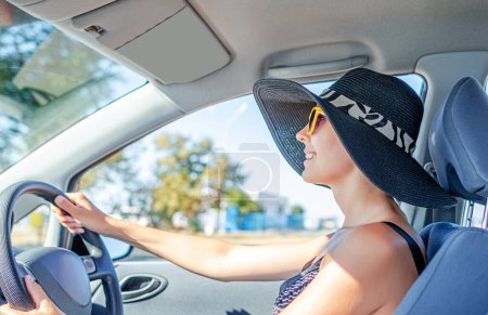 Téléchargez les photos : Belle jeune femme dans une voiture souriant en lunettes de soleil jaunes. - en image libre de droit