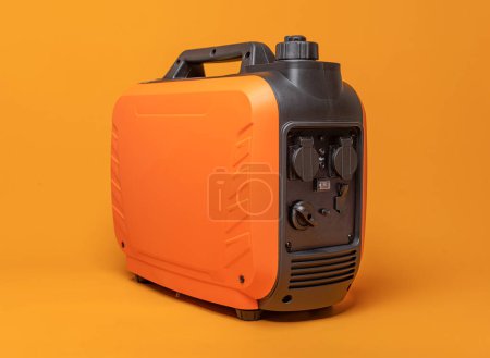 Téléchargez les photos : Electricity generator. Inverter gasoline generator on an orange background. Studio shot. - en image libre de droit