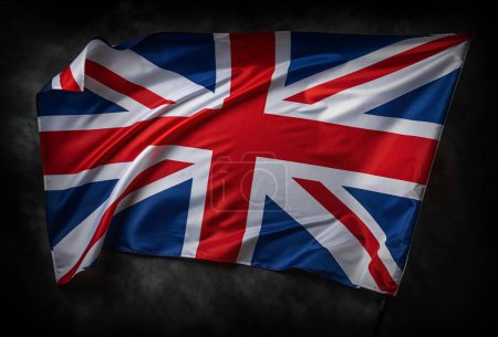 Téléchargez les photos : The UK flag waving in the wind against a dark background. - en image libre de droit