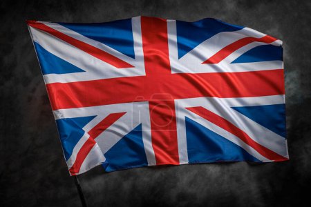 Téléchargez les photos : The UK flag waving in the wind against a dark background. - en image libre de droit