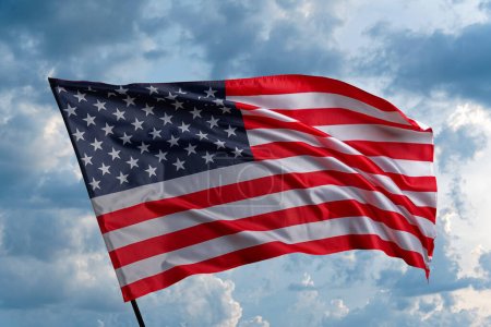 Téléchargez les photos : American flag on the blue sky. The American flag waving in the blue sky. - en image libre de droit