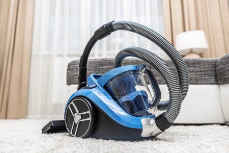Modern vacuum cleaner in the living room. Vacuum cleaner on the background of the home interior.