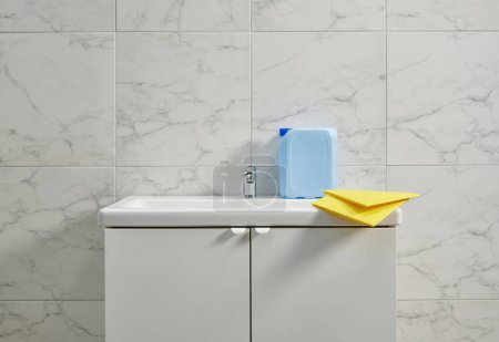 Téléchargez les photos : Kits de nettoyage sur l'évier de l'armoire dans la salle de bain, tissu jaune, gros plan. - en image libre de droit
