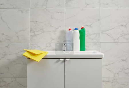Foto de Kits de limpieza en el fregadero del gabinete en la sala de baño, tela amarilla, primer plano. - Imagen libre de derechos