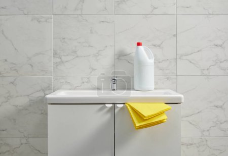 Foto de Kits de limpieza en el fregadero del gabinete en la sala de baño, tela amarilla, primer plano. - Imagen libre de derechos
