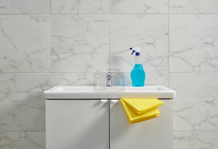 Téléchargez les photos : Kits de nettoyage sur l'évier de l'armoire dans la salle de bain, tissu jaune, gros plan. - en image libre de droit