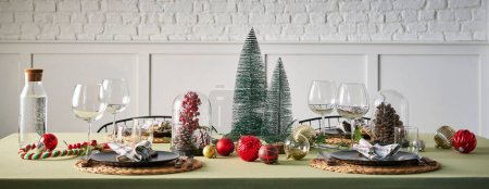 Foto de Servicio de mesa de Navidad y año nuevo, mantel verde, accesorio, árbol, interior, pared de ladrillo blanco. - Imagen libre de derechos