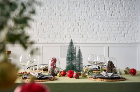 Foto de Servicio de mesa de Navidad y año nuevo, mantel verde, accesorio, árbol, interior, pared de ladrillo blanco. - Imagen libre de derechos