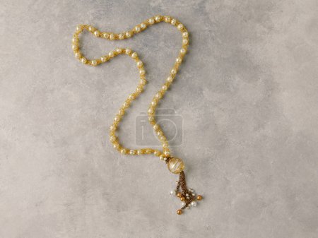 Foto de Yellow rosary.Product still life concept. Modern and decorative textured background. - Imagen libre de derechos