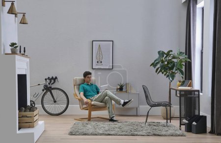 Foto de Adolescente persona masculina que trabaja y estudio lección en la habitación, decorativo estilo interior, mesa de la silla y diseño de la planta. - Imagen libre de derechos