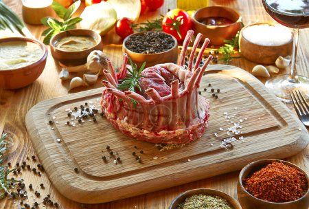 Téléchargez les photos : Viande non cuite sur la planche à découper fond de tomate et d'épices, délicieux repas. - en image libre de droit
