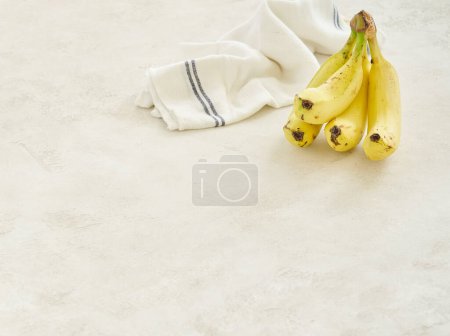 Photo for Bananas are on the grey concrete table, close up, white and blue napkin background. - Royalty Free Image