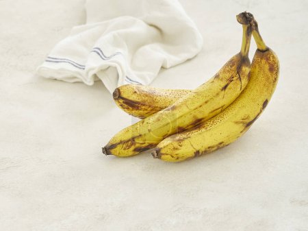 Photo for Bananas are on the grey concrete table, close up, white and blue napkin background. - Royalty Free Image
