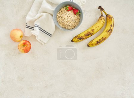 Photo for Bananas apple and granola in the cup, grey background top view. - Royalty Free Image