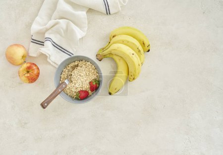 Photo for Bananas apple and granola in the cup, grey background top view. - Royalty Free Image