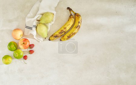 Foto de Las frutas están sobre la mesa fondo de hormigón gris, plátano manzana y servilleta, disparado desde arriba - Imagen libre de derechos