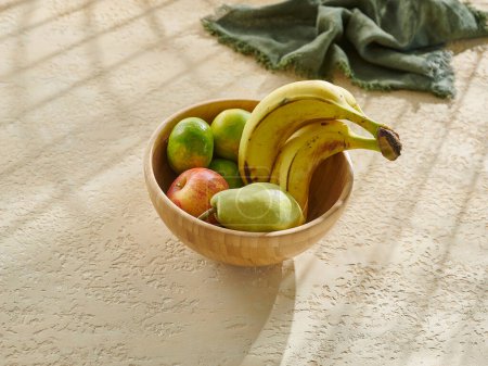 Téléchargez les photos : Divers fruits dans un bol et une tasse sur la table en bois. Banane, pomme, poire et mandarine. - en image libre de droit