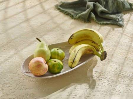 Téléchargez les photos : Divers fruits dans un bol et une tasse sur la table en bois. Banane, pomme, poire et mandarine. - en image libre de droit