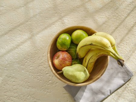 Photo for Various fruits in bowl and cup on the wooden table. Banana, apple, pear and tangerine. - Royalty Free Image