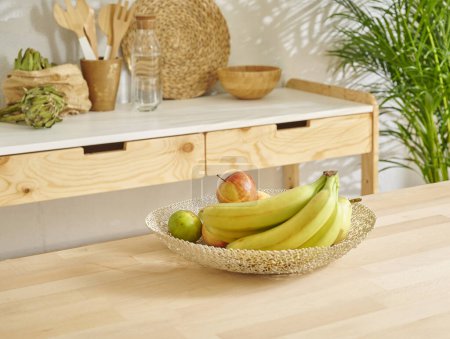 Photo for Banana and various fruits in the basket, decorative wooden kitchen interior. - Royalty Free Image