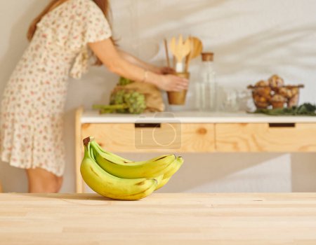 Téléchargez les photos : Banane sur la table en bois et fond de cuisine style. Contexte de la femme. - en image libre de droit