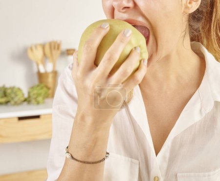 Téléchargez les photos : Femme mangeant des pommes, gros plan, bouche et main. Style de fond de cuisine. - en image libre de droit