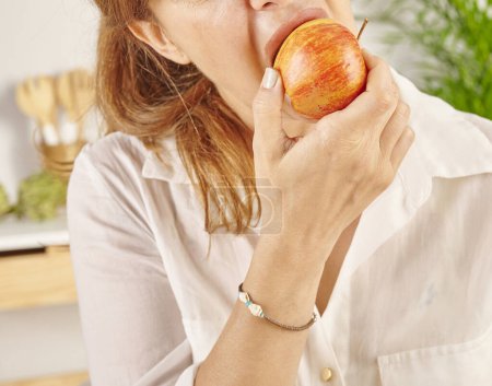 Foto de Mujer comiendo manzana, primer plano, boca y mano. Estilo de fondo de cocina. - Imagen libre de derechos