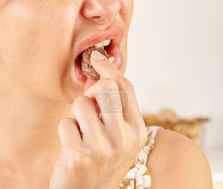 Téléchargez les photos : Femme mangeant biscuit, gros plan, la main et la bouche. - en image libre de droit