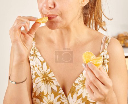 Photo for Woman eating mandarin, close-up, hand and mouth. - Royalty Free Image
