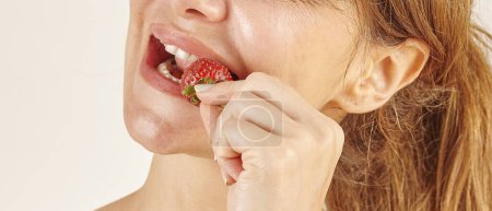 Photo for Woman eating strawberry, close-up, hand and mouth. - Royalty Free Image