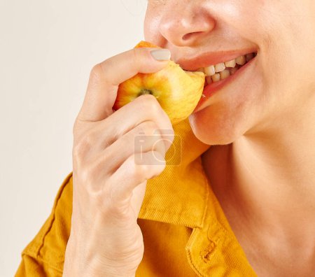 Téléchargez les photos : Femme mangeant des pommes, gros plan, la main et la bouche. Fond de cuisine. - en image libre de droit