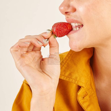 Foto de Mujer comiendo fresa, primer plano, mano y boca. Fondo de cocina. - Imagen libre de derechos
