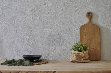 Photo for Kitchenware is on the wooden table close up, cutting board vase of plant, plate, spoon, fork, water glass. - Royalty Free Image