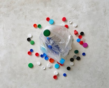 Foto de Las botellas y tapas de plástico están en la mesa verde, reciclando el concepto de residuos. - Imagen libre de derechos