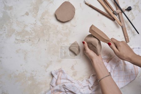 Foto de Fabricación de cerámica, manos de las mujeres y herramientas en el fondo decorativo de estilo de mesa, ver. - Imagen libre de derechos