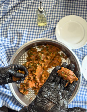 Téléchargez les photos : Steak tartare style turc, pétrir dans un bol en métal, main d'homme, en utilisant des gants, la culture traditionnelle, la fabrication de boulettes de viande crues. - en image libre de droit