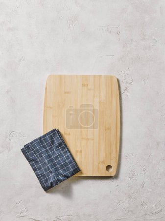 Foto de Tabla de cortar de madera en la mesa decorativa, vista desde arriba, servilleta, fondo vacío y texturizado. - Imagen libre de derechos