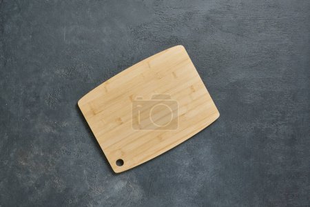 Foto de Tabla de cortar de madera en la mesa decorativa, vista desde arriba, servilleta, fondo vacío y texturizado. - Imagen libre de derechos