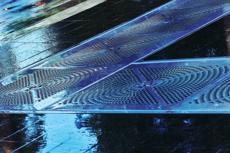 Foto de Suelo de pavimento de baldosas húmedas con rejillas metálicas de alcantarillado para drenaje de agua - Imagen libre de derechos