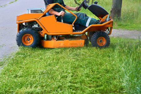 Téléchargez les photos : Coupe d'herbe professionnelle sur les pelouses avec une mini tondeuse à gazon tracteur. - en image libre de droit