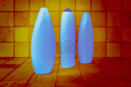 Foto de Botellas brillantes azules de plástico para detergentes cuadrados de fondo de madera naranja - Imagen libre de derechos