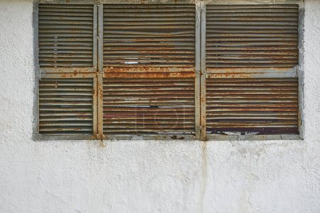 Photo for Old rusty gray grille ventilation holes lattice, wall covered with stone chips - Royalty Free Image