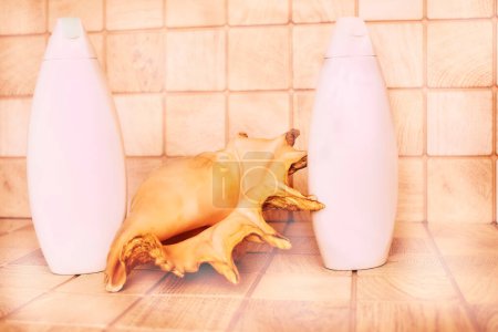 Foto de Botellas de plástico rosa detergente, concha de mar grande, champú - Imagen libre de derechos